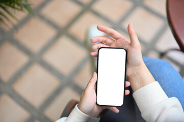 Close-up image of an Asian woman using her phone while relaxing in her home backyard.