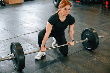 Fototapeta na wymiar Ready to lift the barbell. Beautiful strong woman is in the gym