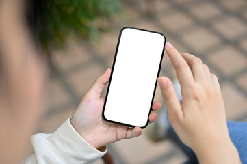 Close-up image of an Asian woman using her phone while relaxing in her home backyard