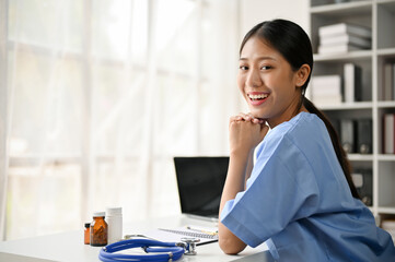 Young Asian medical student smiling and sitting in the study room.