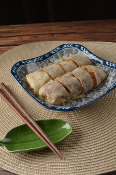 traditional peranakan nonya popiah healthy spring roll wrap with mixed vegetables and sweet sauce on chinese old retro plate and chopstick on wood table halal local vegan food appetiser snack menu