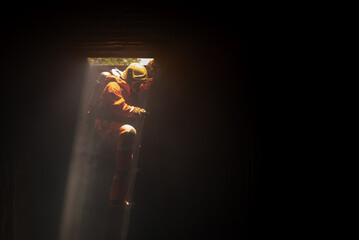 Firefighters are climbing down ladder with sunlight coming from outside of a dark room.