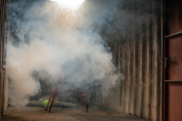 Ladder is covered in smoke and there is a dummy of a victim lying in the galvanized room with soft light.