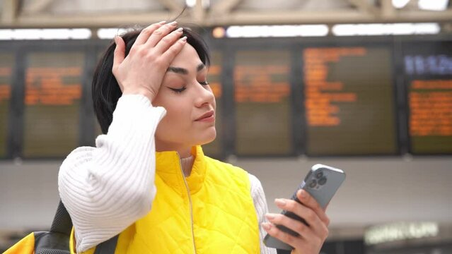 a young woman in a yellow waistcoat   with a smartphone in her hands was late and missed the train at the railway stations travel concept