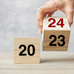 hand flipping block 2023 to 2024 text on table. Resolution, strategy, plan, goal, motivation,...
