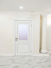 Interior of a room with white door and marble floor, nobody inside