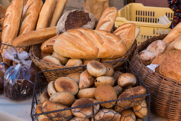 Different types of fresh bread for sale on the table in an outdoor market.