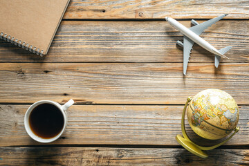 Travel background with notepad, globe, coffee cup and airplane model, top view.