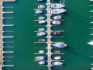 Aerial view of the many white yachts and sailboats moored in the marina on the turquoise water,...