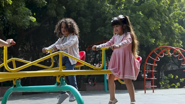 Two happy children playing on a seesaw in a park