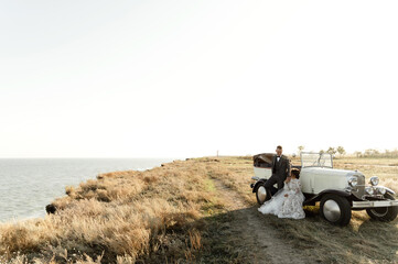 bride and groom after the wedding ceremony at sunset. unique wedding car. newlyweds on the background of the sea. portrait of a wedding couple in nature