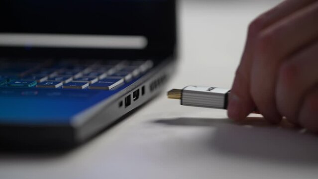 Detail cropped shot of unrecognizable man inserting HDMI cable into side port of laptop computer. Closeup male hands plugging HDMI cable inserted into socket. Shooting in slow motion.
