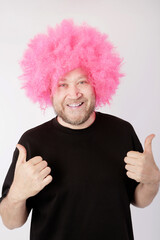 smiling man with pink afro wig