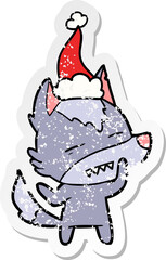 hand drawn distressed sticker cartoon of a wolf showing teeth wearing santa hat