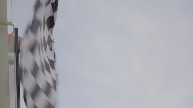 Man holding and waving Checkered race at finish line on a raceway F1. Victory, achievement, success and sport concept. 