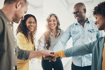Laughing team of diverse businesspeople standing with their hands together