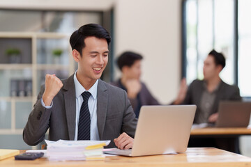 Asian Businessperson using laptop and celebrating victory and success, have good news, job celebrating achievement.