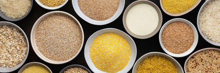 Various grain cereals in bowls banner, top view on a brown background with bowls of cereals and ears of oats