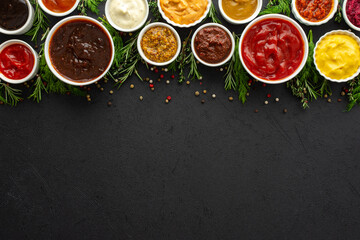 Obraz na płótnie Canvas Different types of sauces in bowls with seasonings, rosemary and dill, thyme and and peppercorns, top view, copy space