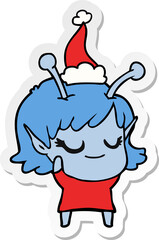 smiling alien girl hand drawn sticker cartoon of a wearing santa hat