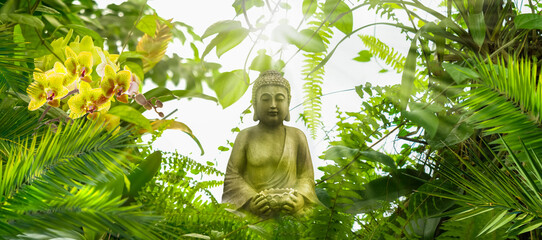 smiling buddha statue in a fresh wild green tropical garden, asian spirit nature background for...