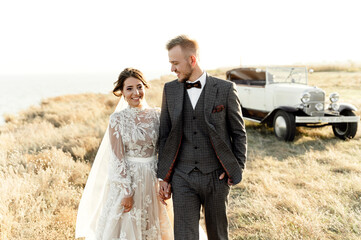 a young wedding couple after the ceremony walks on a hilltop overlooking the sea. bearded groom...