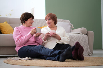 Timeless friendship: Two happy senior women bonding over tea and engaging in heartfelt...