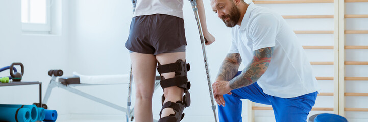 The girl after a stroke with an orthosis on a crutch leg is exer