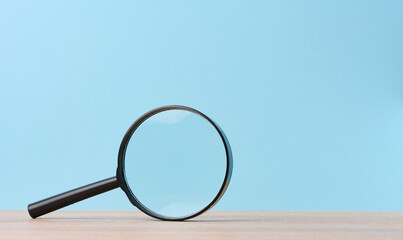 Black magnifier on a blue background. The concept of uncertainty and the search for solutions,...