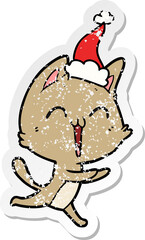 happy hand drawn distressed sticker cartoon of a cat meowing wearing santa hat