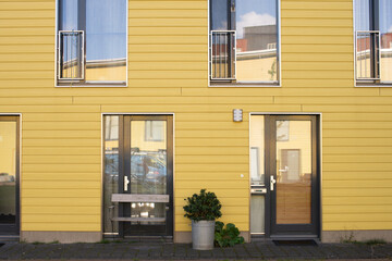 A house with a yellow facade and large windows. Street view of the yellow house