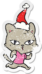 hand drawn distressed sticker cartoon of a cat out for a run wearing santa hat