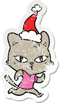 hand drawn distressed sticker cartoon of a cat out for a run wearing santa hat