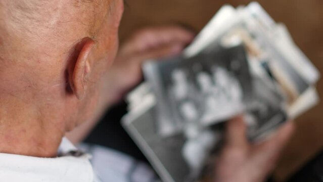 an elderly man looks at old family photos, selective focus. family tree, emotions of the elderly, memories and nostalgia of the old man