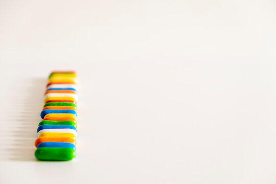 Delicious colored sweet licorice candies in capsules or pills on a white background, forming a vertical line, with space for text, copy space.