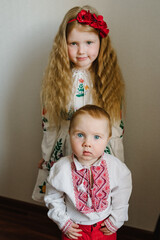 Kids dressed in Ukrainian folk embroidered clothes. National ethnic traditional costume or dress. A child girl with wreath of poppies on his head. Ukrainian customs, traditions.