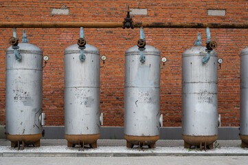 Old industrial metal tanks against brick wall
