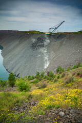 Backfilling of the spent iron ore quarry with a walking excavator in the evening