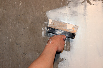 putty. Man plastering wall with putty knife indoors, closeup. home renovation