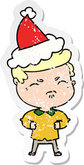 hand drawn distressed sticker cartoon of a annoyed man wearing santa hat