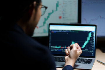 Successful Businessman Sitting at Desk Using Laptop Computer, Celebrate Success. Entrepreneur in Suit working with Stock Market App Smiles, Happy Victory. Motion Blur Background.