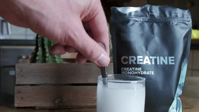 Close up of a hand mixing creatine monohydrate in a glass 4K slow motion