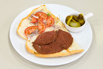 Fototapeta na wymiar Close-up shot of Izmir's famous Turkish Traditional Kumru Sandwich, Çeşme Kumru , ingredients ready to eat salami, sucuk , tomato, cheddar cheese and fried cheese. Yengen eritme karisik sandvic.