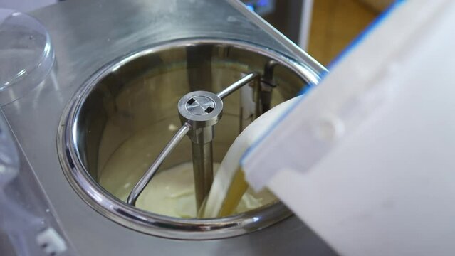 Adding vanilla ice cream from bucket to the pasteurization machine in a factory. High quality 4k footage