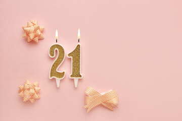 Number 21 on a pastel pink background with festive decorations. Happy birthday candles. The concept...