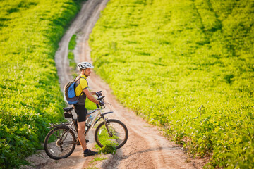 Fototapeta na wymiar Young cyclist cycling in the spring meadow