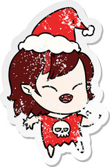 hand drawn distressed sticker cartoon of a laughing vampire girl wearing santa hat