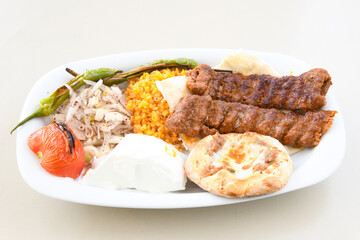Grilled Turkish Adana, Urfa  Kebab with grilled vegetables, onion and rice on plate. Adana durum.