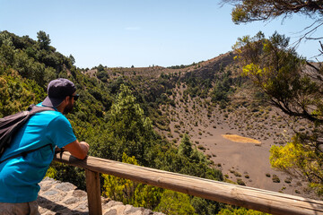 Fototapeta na wymiar A young man at the Fireba volcano viewpoint of La Llania park in El Hierro, Canary Islands. Next to El Brezal the humid forest