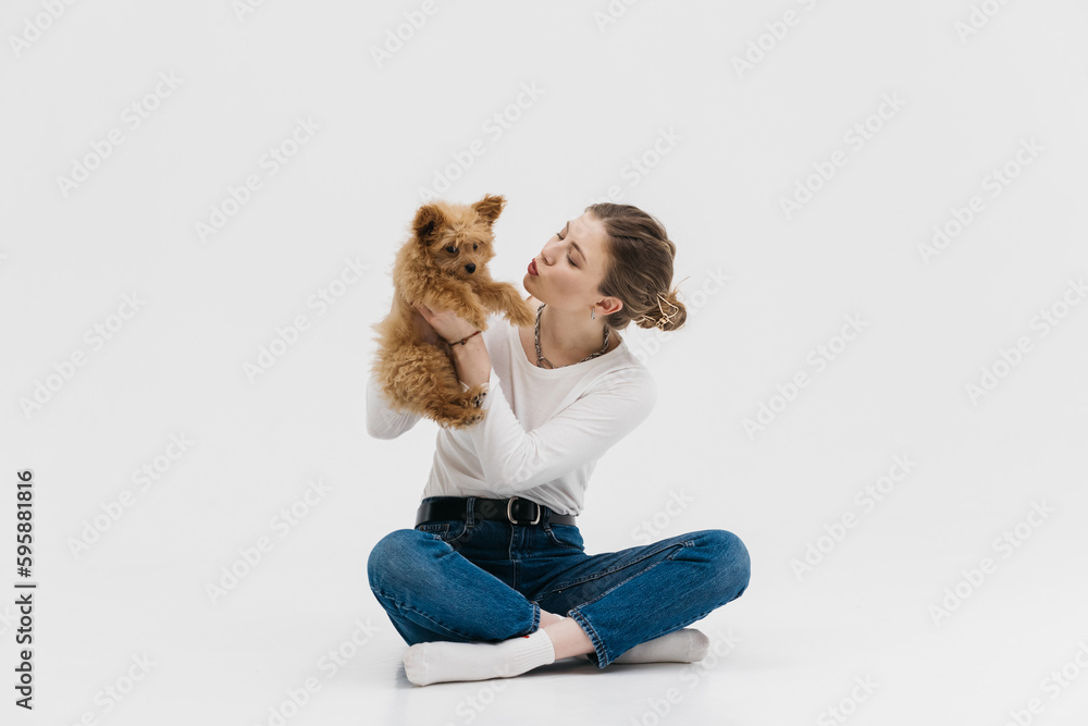 Wall mural a cute young woman kisses and hugs her puppy. love between owner and dog. isolated on white backgrou